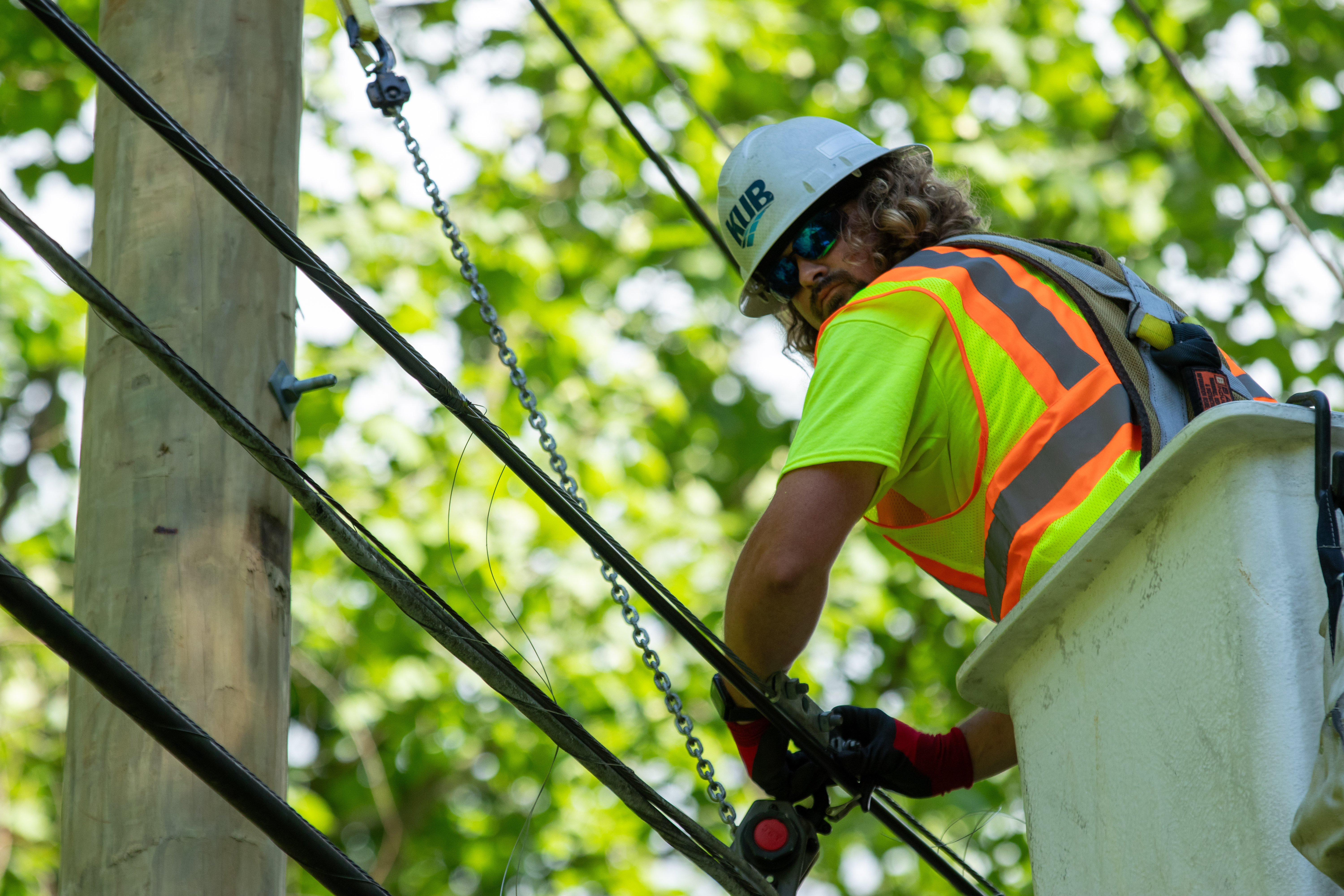 Construction is underway aerially for KUB Fiber wiring. A team member is in a bucket truck working on this.